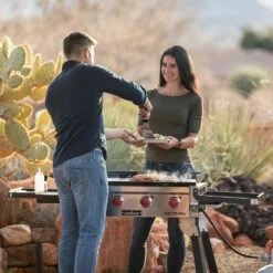 Camp Chef 30-Inch 4-Burner Freestanding / Countertop Propane Gas Commercial Style Flat Top Griddle -BBQDIRECT Shop Camp Chef 30 Inch 4 Burner Tabletop Freestanding Flat Top Griddle FTG600P Lifestyle Couple